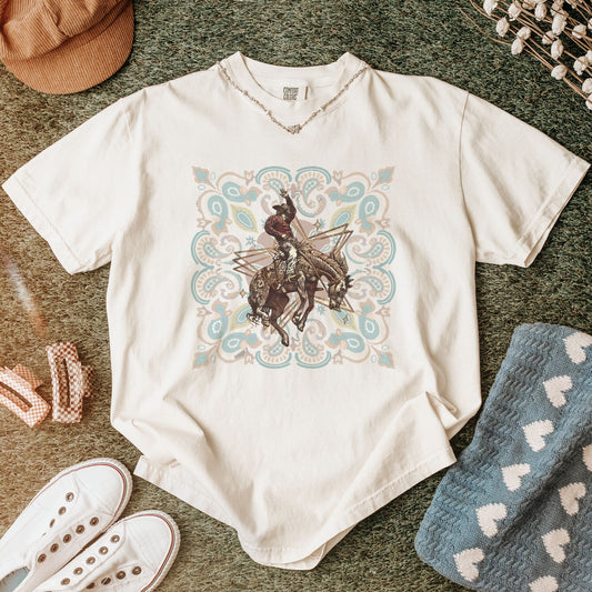 Rodeo spirit bronco tee laid out with props in color ivory