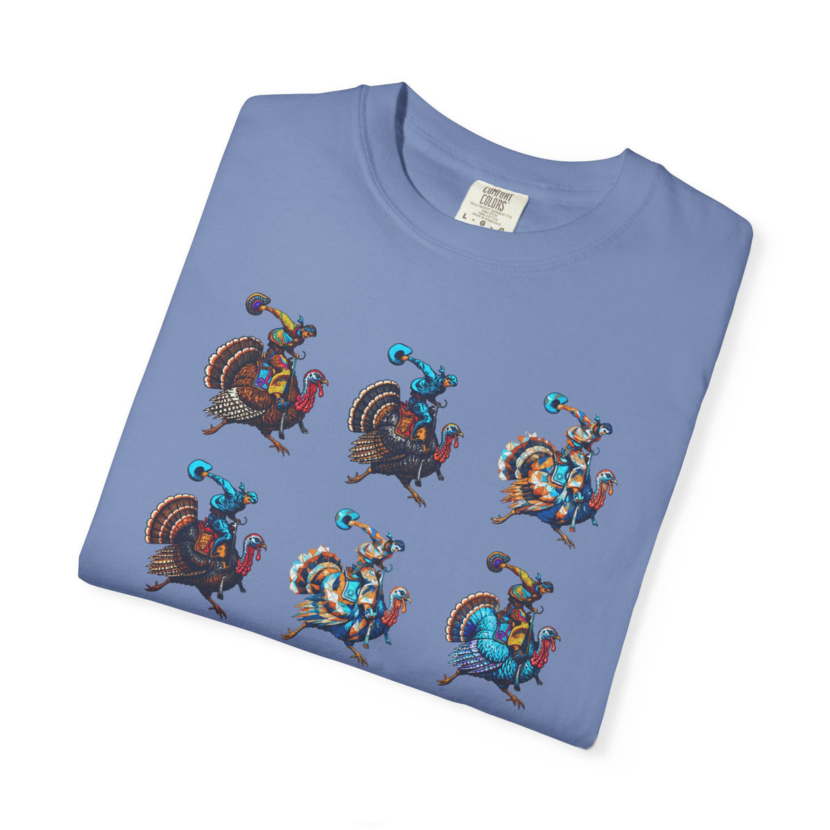 A folded light blue crewneck t-shirt featuring a graphic print of six cartoon turkeys riding blue and orange characters, displayed on a clean white background.