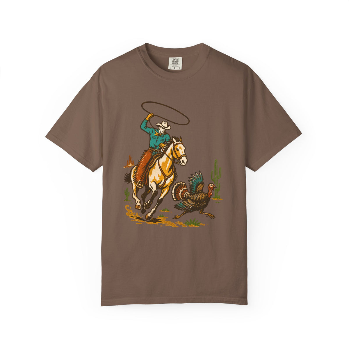 A brown short-sleeve crewneck t-shirt featuring a western-themed graphic print of a cowboy on a galloping horse trying to rope a turkey, displayed on a clean white background.