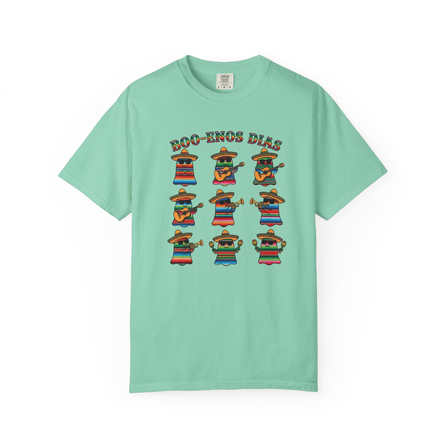 A mint green short-sleeve t-shirt with a colorful graphic print on the front. The graphic features the text 'BOO-TENOS DIAS' above nine cartoon characters wearing sombrero and colorful striped serapes, posed in different dancing stances.