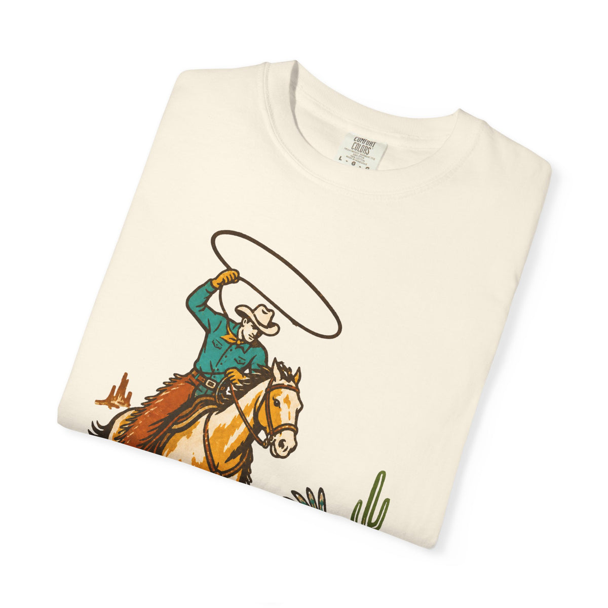 An off-white folded t-shirt with a vintage-style western graphic of a cowboy on a horse swinging a lasso, displayed on a clean white background.