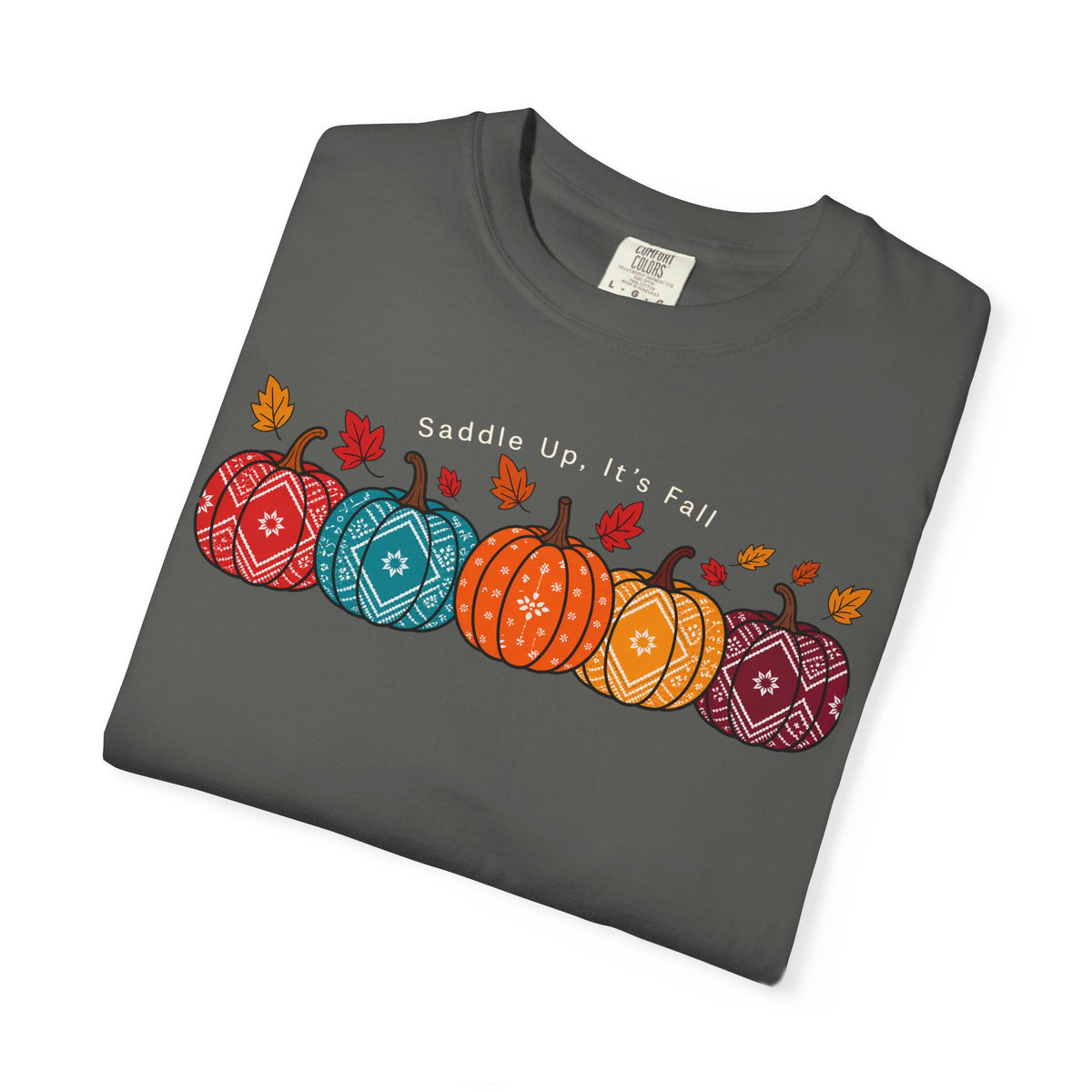 A dark gray folded t-shirt featuring a colorful graphic of three patterned pumpkins, autumn leaves, and the text 'Saddle Up, It's Fall' on a white background.