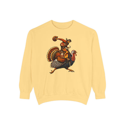 A pale yellow crewneck sweatshirt featuring a graphic print of a cowboy riding a turkey and holding a football, displayed on a clean white background.