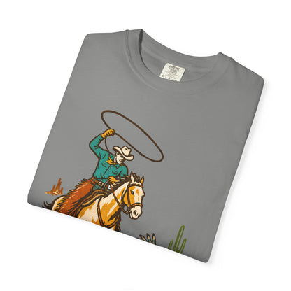 A folded gray crewneck t-shirt with a western-themed graphic of a cowboy on a horse swinging a lasso, displayed on a clean white background.