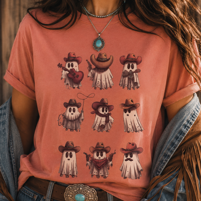 A person wearing a coral pink graphic T-shirt with a grid of cartoon ghosts in cowboy hats and western accessories, paired with a denim jacket and a turquoise pendant necklace.