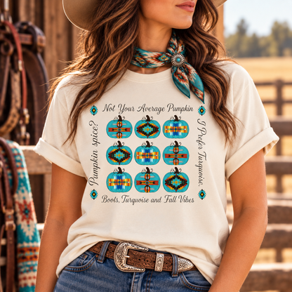 A woman wearing a cream-colored graphic t-shirt with a southwestern-style pumpkin print in turquoise, red, and black. The shirt features the text 'Not Your Average Pumpkin' and 'Pumpkin Spice? Books, Turquoise and Fall Vibes'.