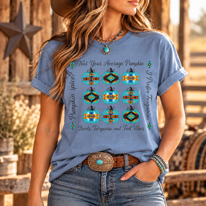 A woman wearing a light blue graphic t-shirt with a southwestern-themed pumpkin print, styled with a brown belt and jeans in a rustic outdoor setting.
