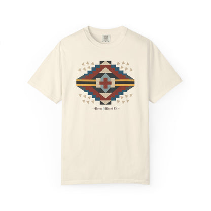 An off-white short-sleeve t-shirt with a colorful geometric Southwestern-style diamond graphic on the chest, featuring the text 'Bronc &  Brand Co.' below the design.