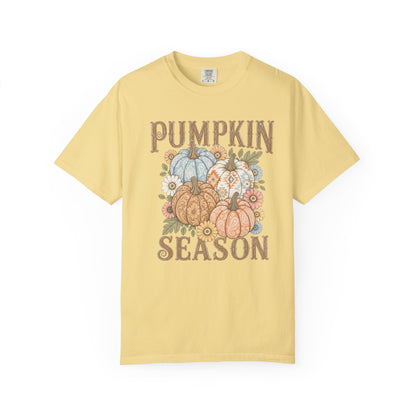 A pale yellow short-sleeve t-shirt with a 'Pumpkin Season' graphic on the front, featuring illustrations of patterned pumpkins and autumn flowers in earthy tones.
