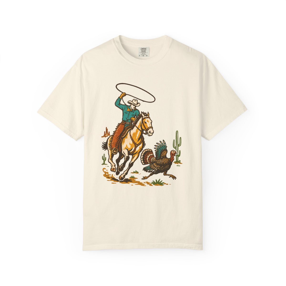 An off-white short-sleeve crewneck t-shirt featuring a colorful retro graphic of a cowboy riding a horse and throwing a lasso, with a turkey and cactus in the scene.