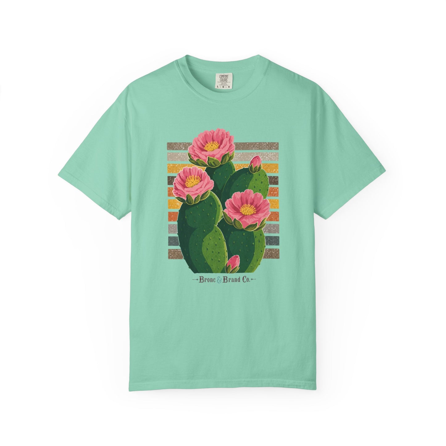 A mint green short-sleeve t-shirt with a graphic print of a green prickly pear cactus with pink flowers, set against a striped background with the text '-Brave. Brand Co.