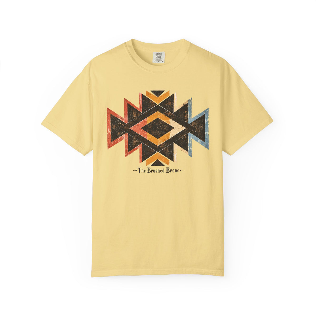 A pale yellow short-sleeve t-shirt with a distressed geometric Southwestern-style diamond graphic in black, orange, red, and blue on the chest, with the text '- The Brushed Bronc-' printed below.