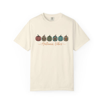 An off-white short-sleeve crewneck t-shirt featuring a graphic of five patterned pumpkins in autumn colors and the text 'Autumn Vibes' in orange cursive across the chest, displayed on a clean white background.