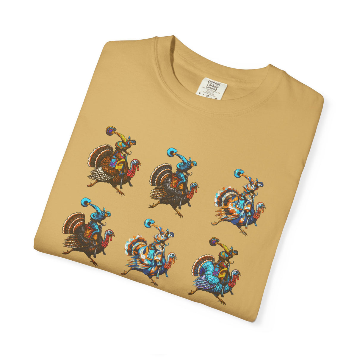 A folded tan crewneck t-shirt with a graphic print of six cartoon turkeys riding blue and orange characters, displayed on a clean white background.