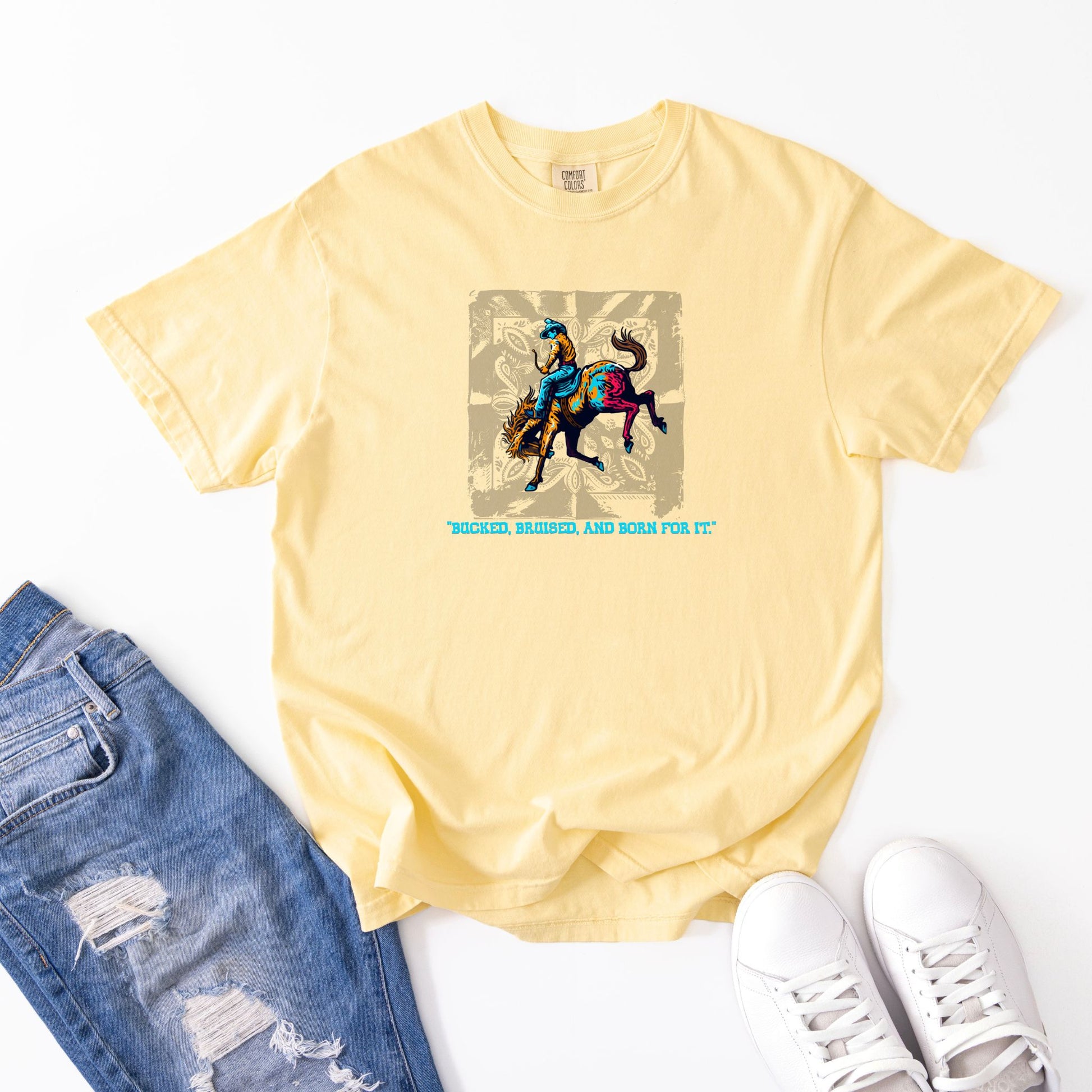Bruised Born & For It Western Tee laid out with jeans and shoes in color butter 