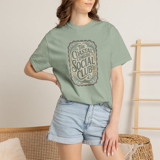 Coastal Cowgirl Clubhouse tee with vintage western sign print and retro coastal colours on model in bay