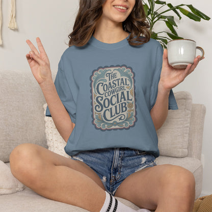 Coastal Cowgirl Clubhouse tee with vintage western sign print and retro coastal colours on model in ice blue