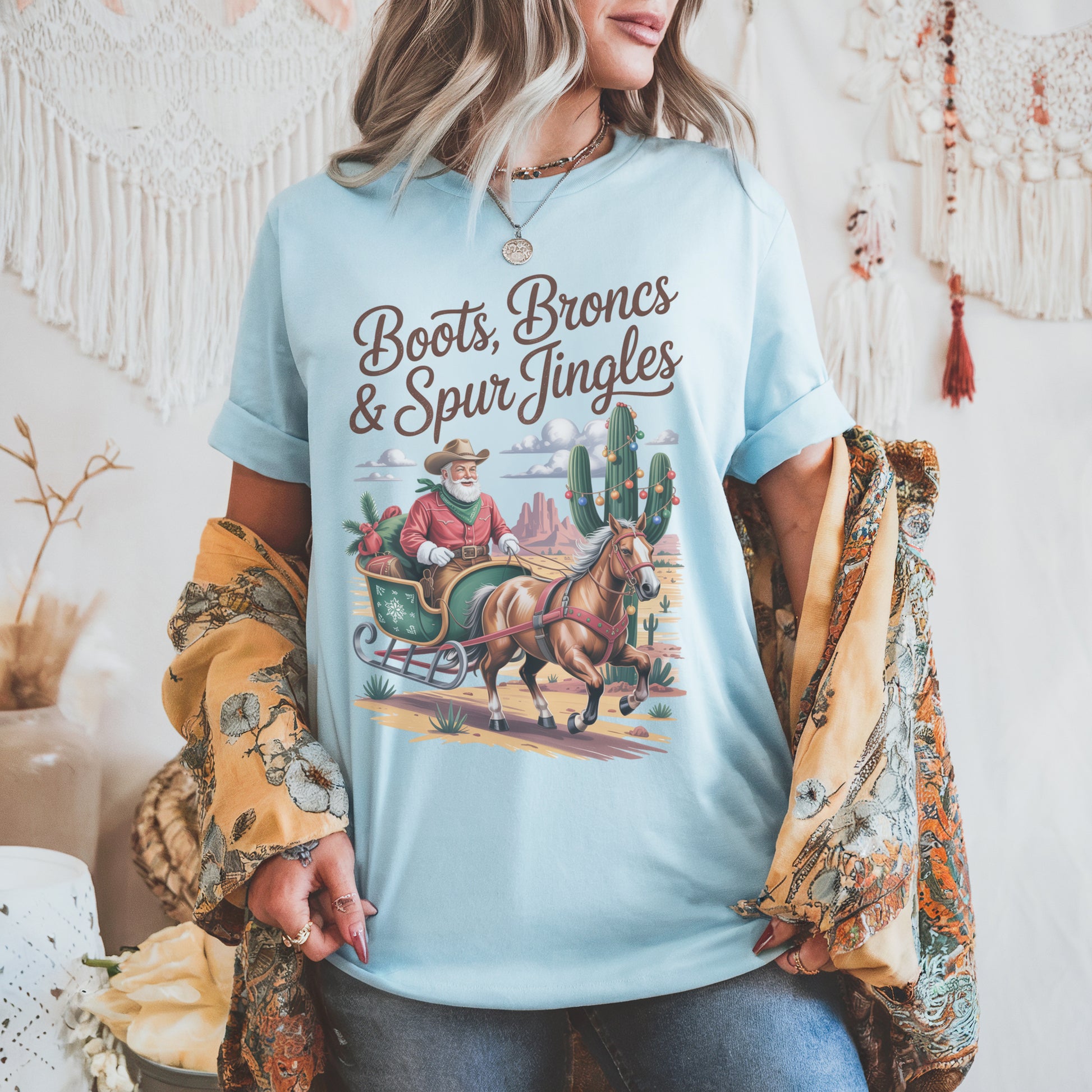 Santa Cowboy Western Christmas t-shirt with Cowboy Santa sleigh, decorated cacti, and desert sunset design